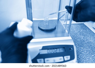 Scientist weighing chemicals by digital scales in grams in chemical laboratory. Blue toning