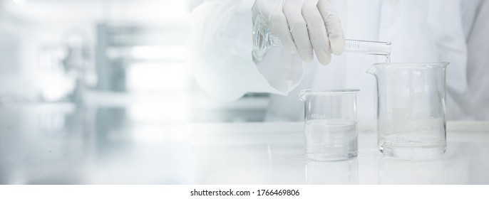 scientist in white coat poring water into glass beaker in medical laboratory science banner background