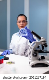 Scientist woman analyzing petri dish with microorganism bacteria in microbiology chemistry hospital laboratory. Biologist researcher working at biochemistry investigation examining microplate