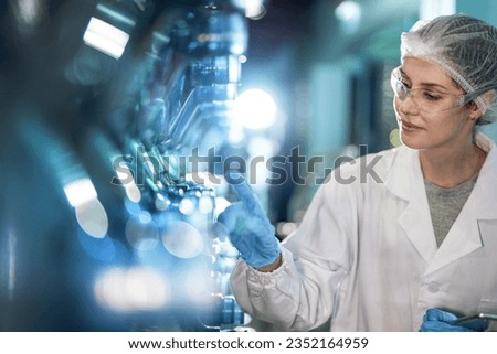 scientist worker checking the quality of water bottles on the machine conveyor line at the industrial factory. Female worker recording data at the beverages manufacturing line production.