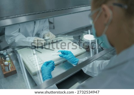 Scientist working inside flow biosafety cabinet. Pathologist team preparing tissue biopsy cassettes for histology processing. Scientists  handling medical samples in sterile laboratory hood.