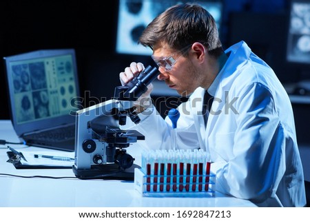 Scientist working in lab. Doctor making microbiology research. Laboratory tools: microscope, test tubes, equipment. Coronavirus covid-19 , bacteriology, virology and health care.