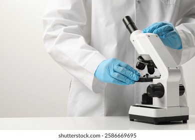 Scientist working with microscope in laboratory, closeup