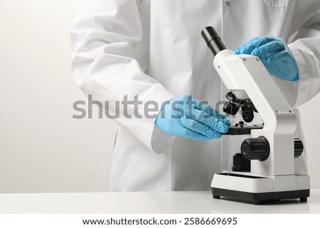 Scientist working with microscope in laboratory, closeup