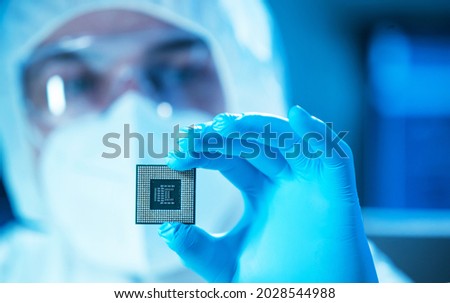 The scientist works in a modern scientific laboratory for the research and development of microelectronics and processors. Microprocessor manufacturing worker uses computer technology and equipment.