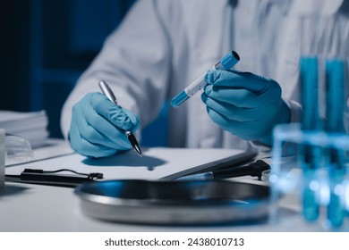 A scientist is writing down the results of an experiment in a report card, A laboratory full of scientific equipment for experiments, Many test tubes were analyzed by experts. - Powered by Shutterstock