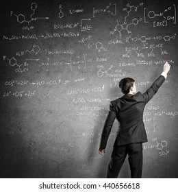 Scientist Writing Formulas On Chalkboard