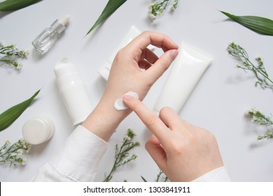 Scientist/Pharmacist applying moisturizer lotion on her hand for efficacy testing of natural organic skincare products in laboratory. Beauty cosmetic research and development concept. Top view.