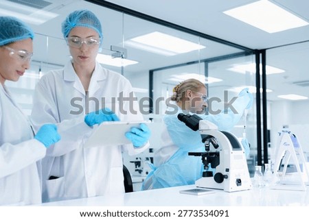 scientists collaborate on assay development, with one performing a critical pipetting step while the other documents the procedure on a tablet for protocol validation under GxP guidelines.