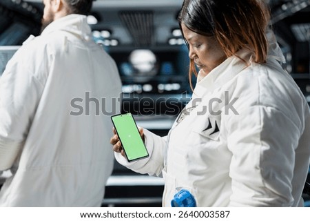 Scientists conduct visual data tests using chroma key smartphone aboard advanced starship during spaceflight. Cosmonauts perform orbital experiments, relying on isolated screen phone for analysis