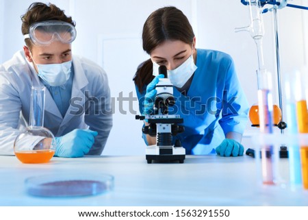 Scientists doing research and analysis with microscope in laboratory