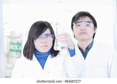 Scientists examining liquid in lab