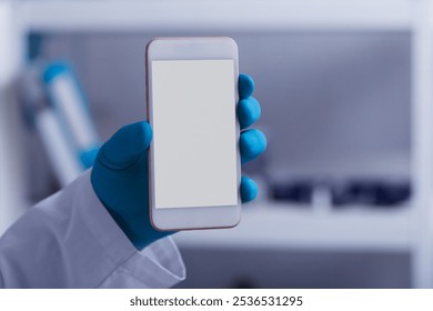 A scientist's hand in a medical glove holds a phone in laboratory - Powered by Shutterstock