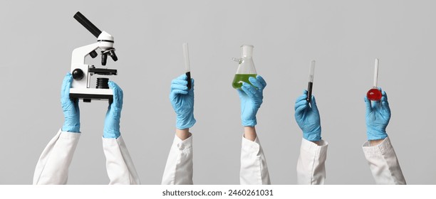 Scientist's hands holding microscope, test tubes with soil and liquids on grey background - Powered by Shutterstock