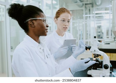 Scientists in laboratory coats performing examination using advanced equipment. Collaborative research environment with professionals wearing protective gear while analyzing data - Powered by Shutterstock