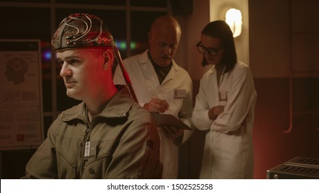 Scientists making experiments on a human brain in a vintage style lab, a man is wearing a sci-fi helmet and researchers are testing him