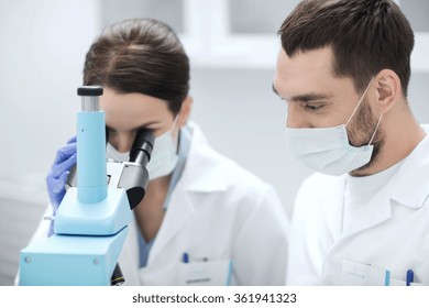 scientists in masks looking to microscope at lab - Shutterstock ID 361941323
