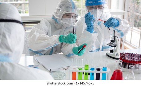 Scientists And Microbiologists With PPE Suit And Face Mask Hold Test Tube With Blood Collected From Patients Covid19, To Create Vaccine For Coronavirus. Covid-19, Laboratory, And Vaccine Concept.