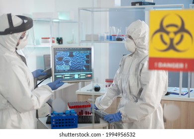 Scientists in ppe suit talking behind the glass wall working in danger area of lab. Group of doctors examining vaccine evolution using high tech for diagnosis against covid19. - Shutterstock ID 1994956532