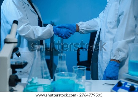 Scientists Shaking Hands in Laboratory Representing Teamwork, Success, and Medical Research Collaboration.