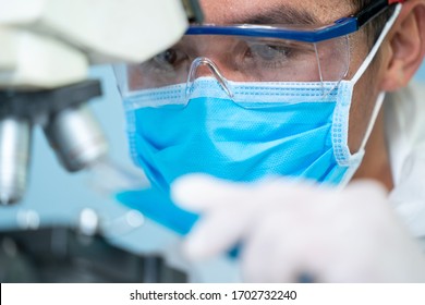 Scientists Working At The Laboratory,close Up Of Doctors In Hazmat PPE Protective Clothing Wear Medical Rubber Gloves Use Microscope In The Laboratory.