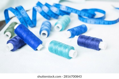Scissors and blue thread spools on white surface, sewing, tools,