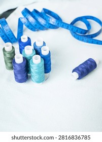 Scissors and blue thread spools on white surface, sewing, tools,