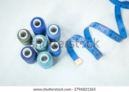 Scissors and blue thread spools on white surface, sewing, tools,