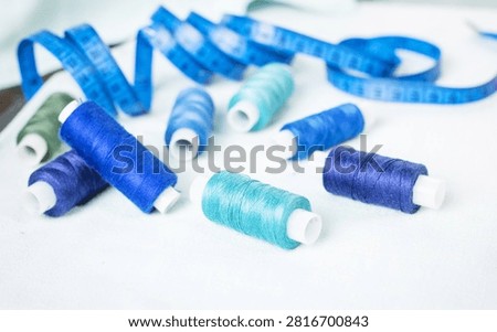 Scissors and blue thread spools on white surface, sewing, tools,