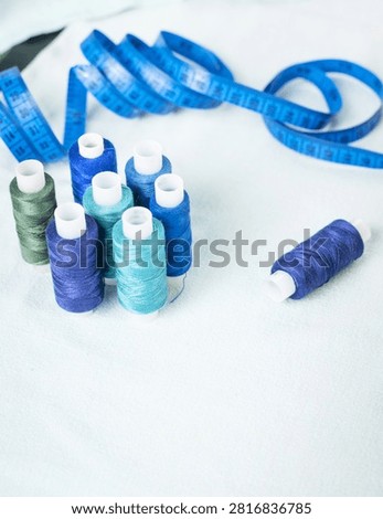 Scissors and blue thread spools on white surface, sewing, tools,