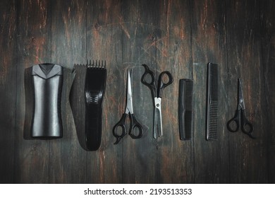 Scissors, combs, shampoo and a men's hair clipper lie in a row on a black wooden background, flat lay close-up. The concept of a male barbershop. - Shutterstock ID 2193513353