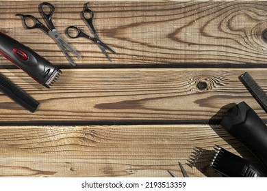 Scissors, Combs, Shampoo And Men's Hair Clippers Lie On The Sides On A Brown Wooden Background With Copy Space In The Center, Flat Lay Close-up. The Concept Of A Male Barbershop.