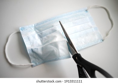 Scissors cut the medical mask. End of the pandemic and restrictions. - Powered by Shutterstock