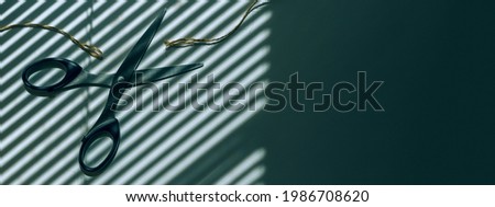 Scissors cut the thread. In the background is a shadow from the blinds. Place for text, hairdresser, office space on the windows of the blinds.