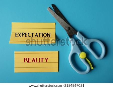 Scissors cut two paper written EXPECTATION and REALITY,  means difference between what was expected and what happened which drives positive and negative human emotions