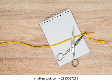 Scissors Cutting Data Cable Over A Blank Spiral Notebook. Concept Of Global Internet Outage