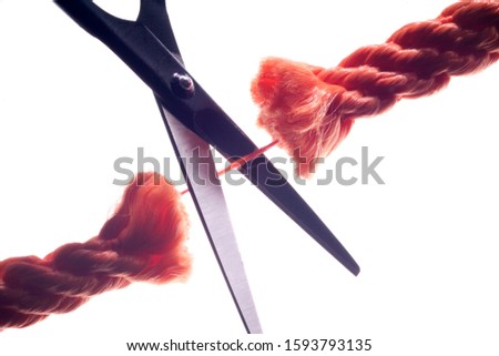 Scissors cutting the last remaining thread of a rope