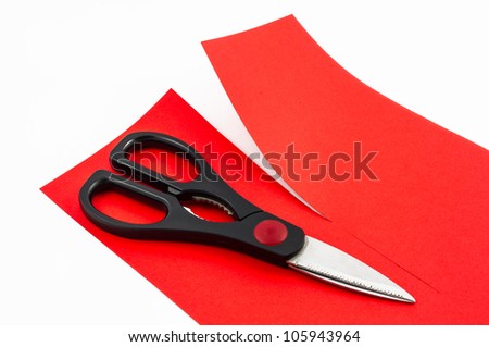 Scissors cutting red paper in two parts