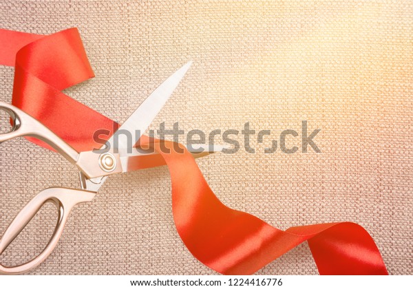 Scissors cutting red ribbon, close-up view on\
blue background