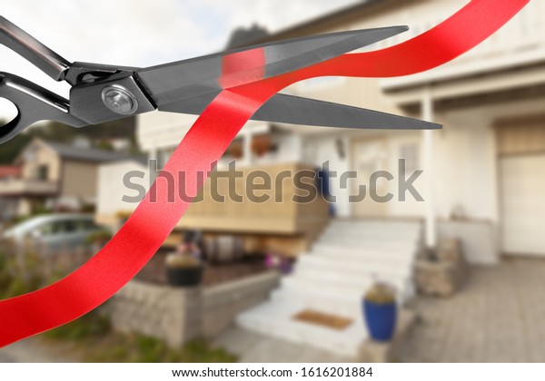 Scissors cutting red ribbon, close-up view on\
white background
