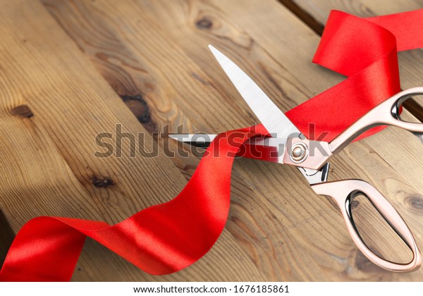 Scissors\
cutting the red ribbon on the wooden\
desk
