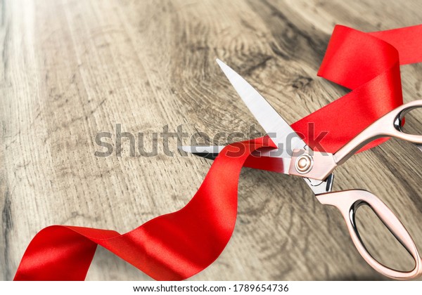 Grand opening, ribbon cut, overhead of gold scissors cutting red
