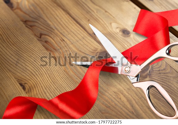 Scissors cutting\
the red ribbon on wooden\
desk