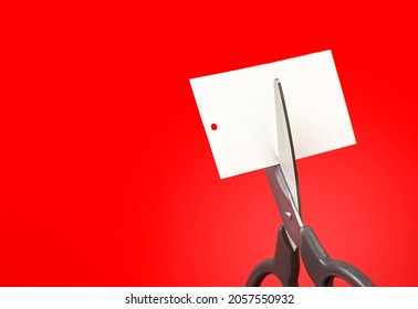 Scissors Cutting A Tag On A Red Background Close Up