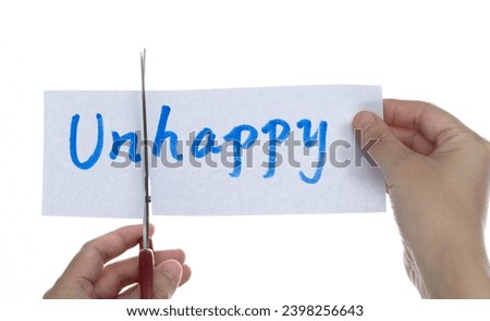 Scissors cutting word unhappy on paper