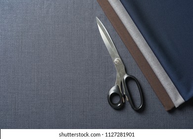 Scissors and fabric samples on cloth, top view. Tailoring equipment