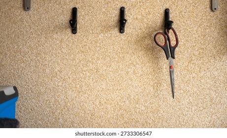 Scissors hanging on wall with hooks in workshop setting.