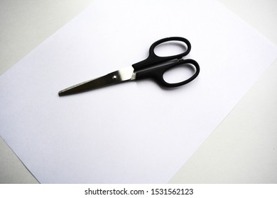 Scissors on the Sheet of Paper. Paper on the table. White Background.