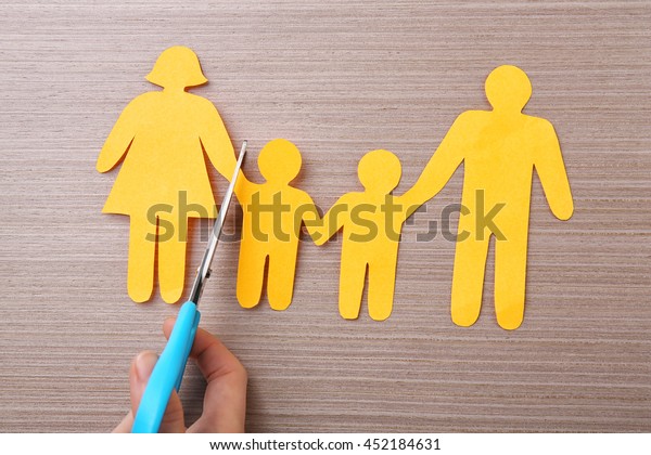 Scissors and paper family on wooden table. Family\
law concept