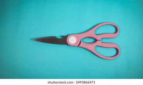 Scissors with pink handles, isolated on a blue background. - Powered by Shutterstock